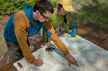Two adults at a picnic table studying a map, one pointing.